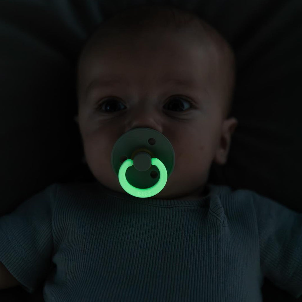 Baby with a glow in the dark BIBS pacifier sold by Meridian Baby.
