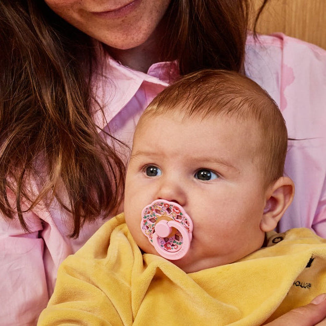 Baby sucking a BIBS Liberty pink pacifier sold by Meridian Baby.