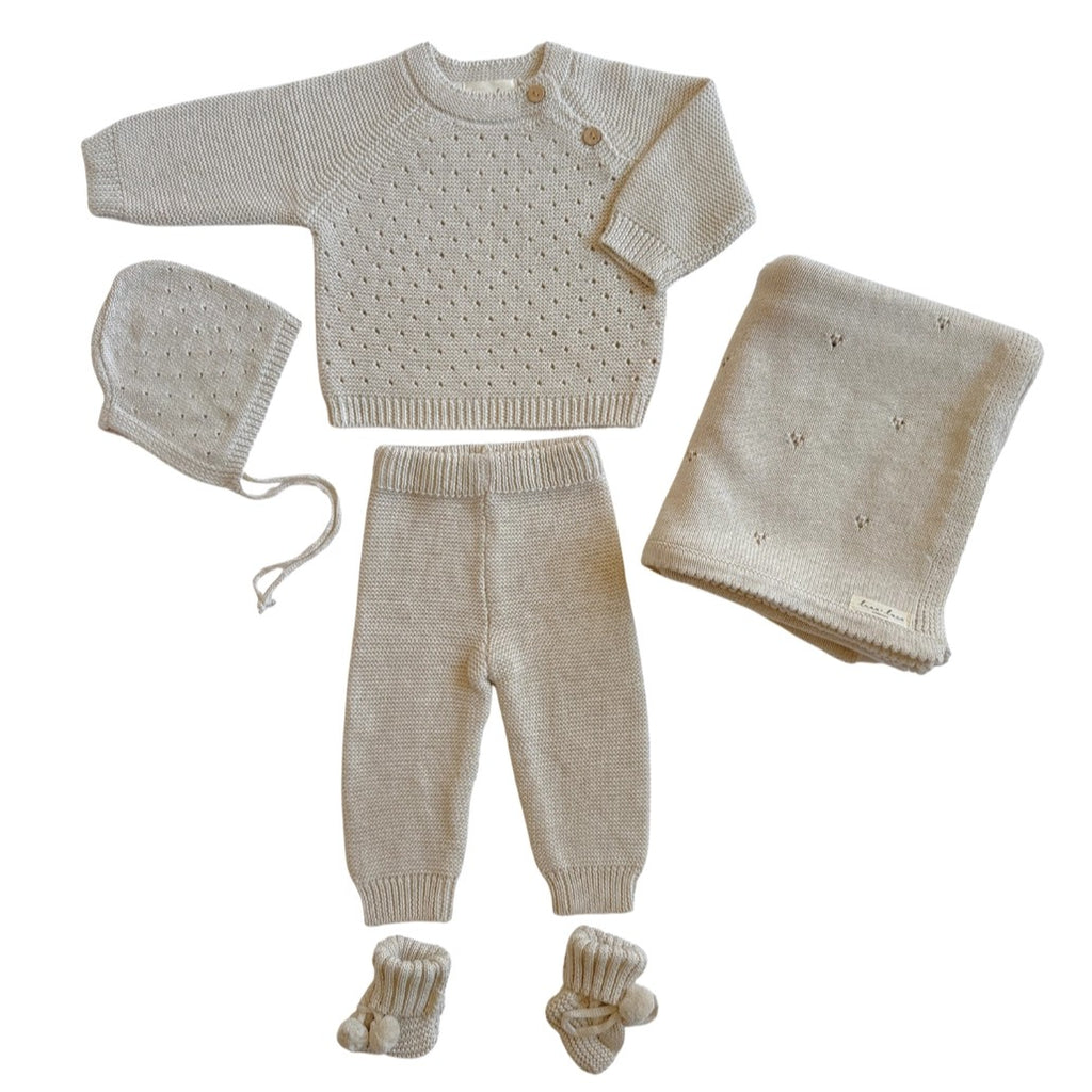 Knitted baby set with blanket, sweater, pants, hat, and booties on a white background
