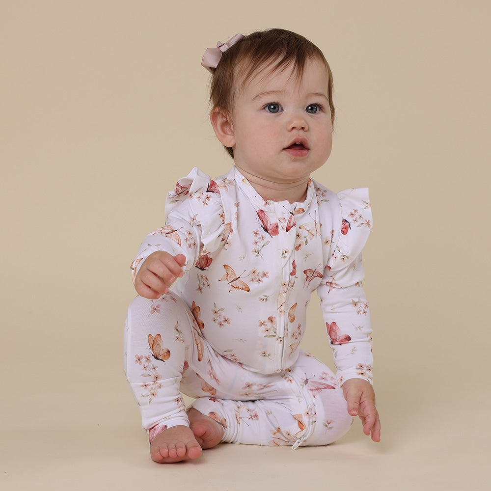 Baby wearing a floral onesie sitting on a beige background