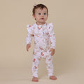 Baby wearing a floral outfit on a beige background