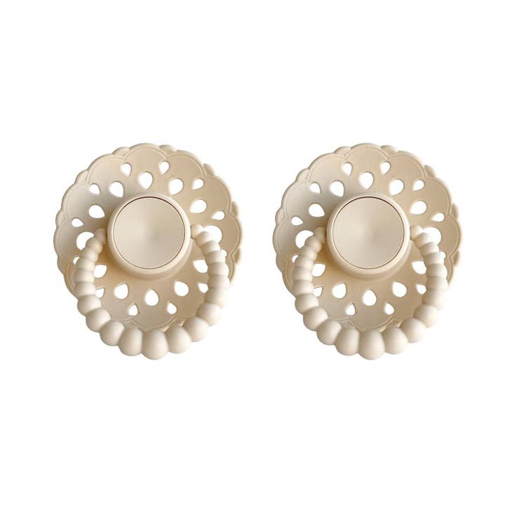 Pair of beige pacifiers with intricate lace-like design on a white background