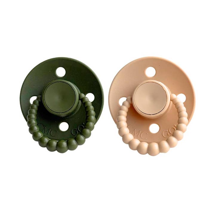 Two pacifiers, one green and one beige, on a white background