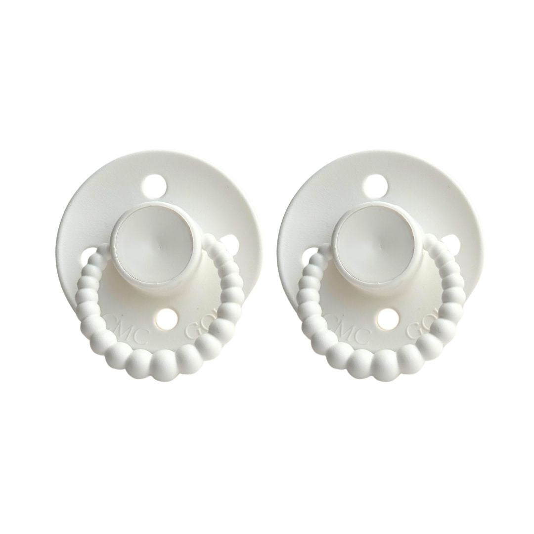 Two white baby pacifiers with decorative beads on a white background