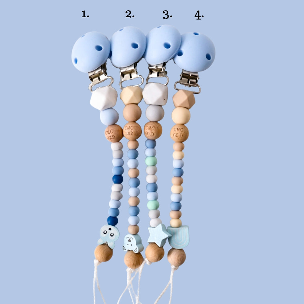Four pacifier clips with colorful beads and attachments on a light blue background