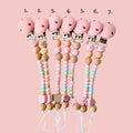 Set of colorful pacifier clips with beads on a pink background