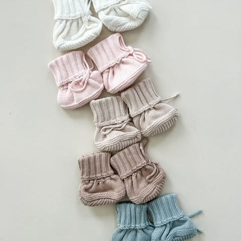 Set of baby booties in various colors on a light gray background