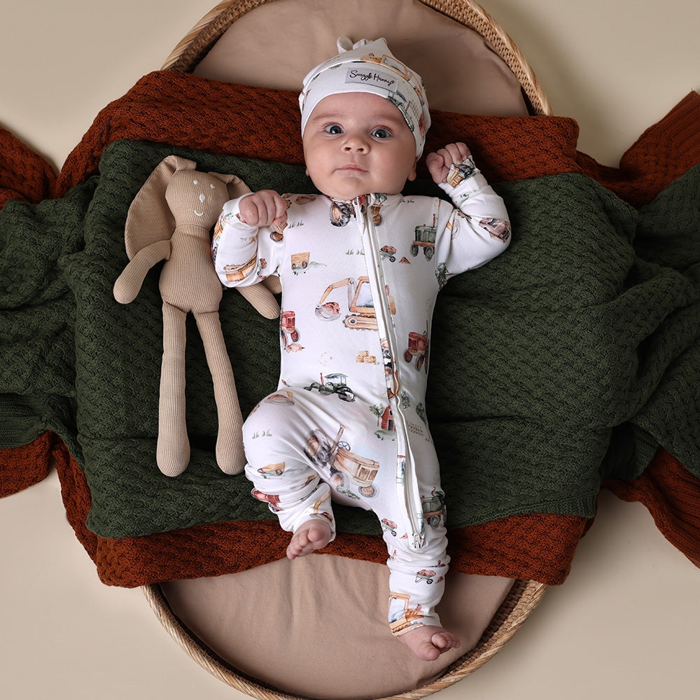 Baby in a patterned outfit with a soft toy in a cozy setting