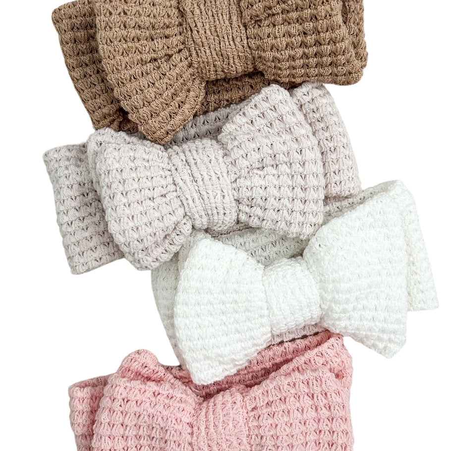 Set of four crocheted hair bows in different colors on a white background