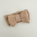 Brown knitted headband with a bow on a light gray background