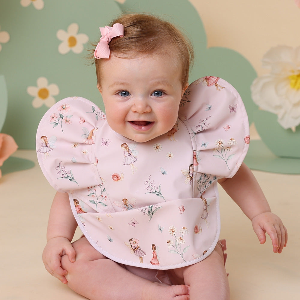 Baby wearing a floral bib with a colorful background
