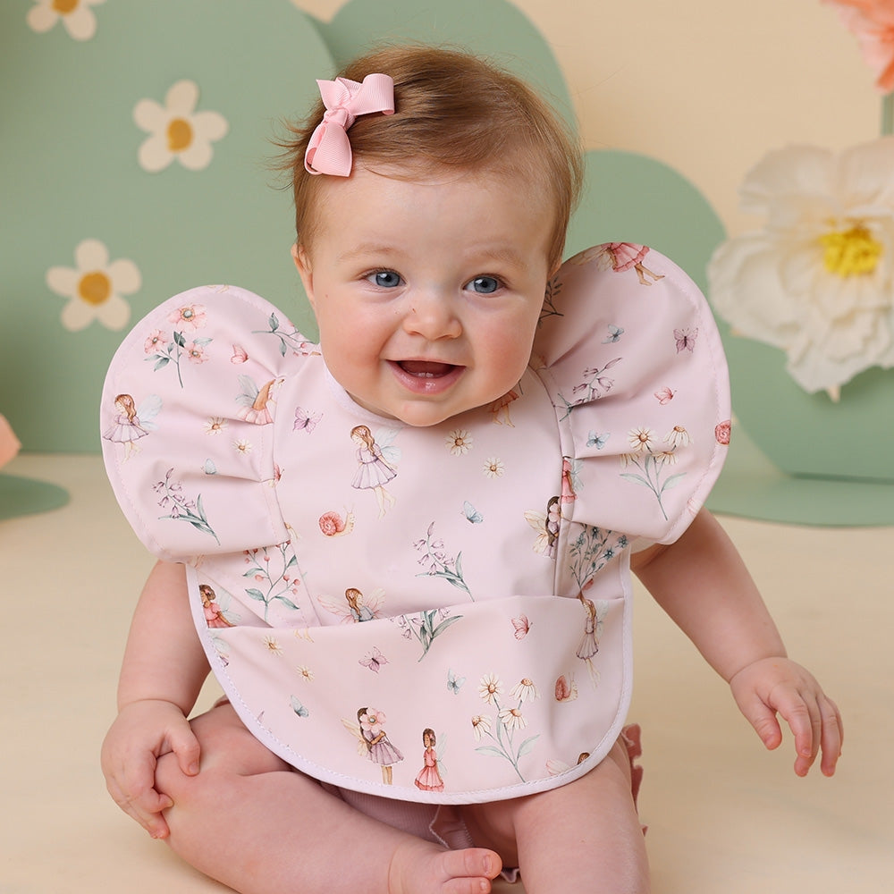 Baby wearing a floral bib with a colorful background