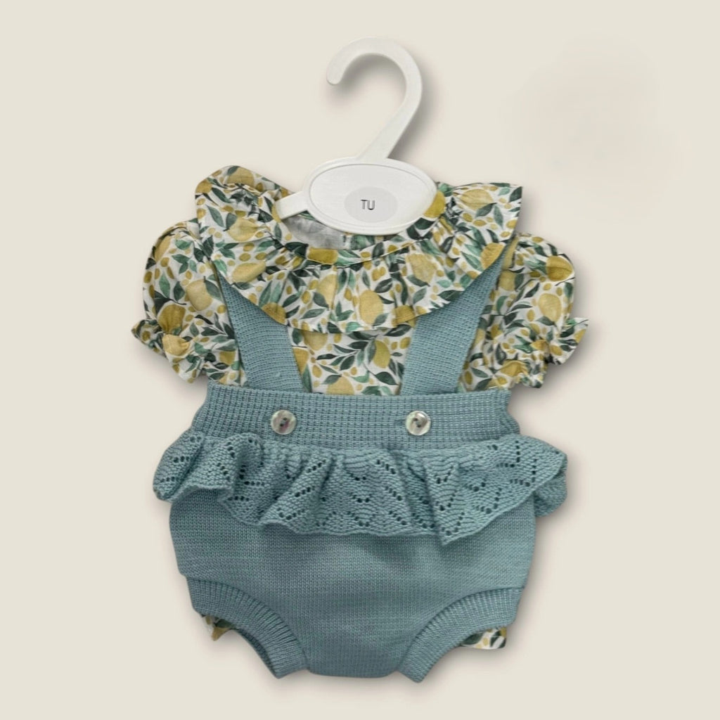 Baby outfit with floral top and blue knitted romper on a beige background