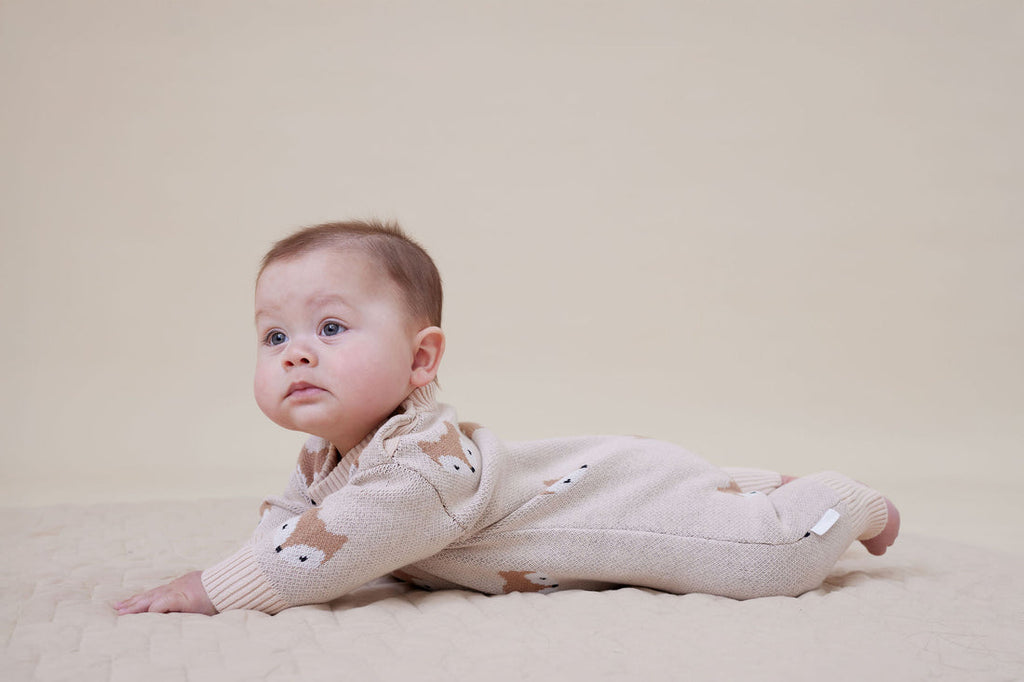 Baby wearing an Aster & Oak beige romper with animal patterns from Meridian Baby