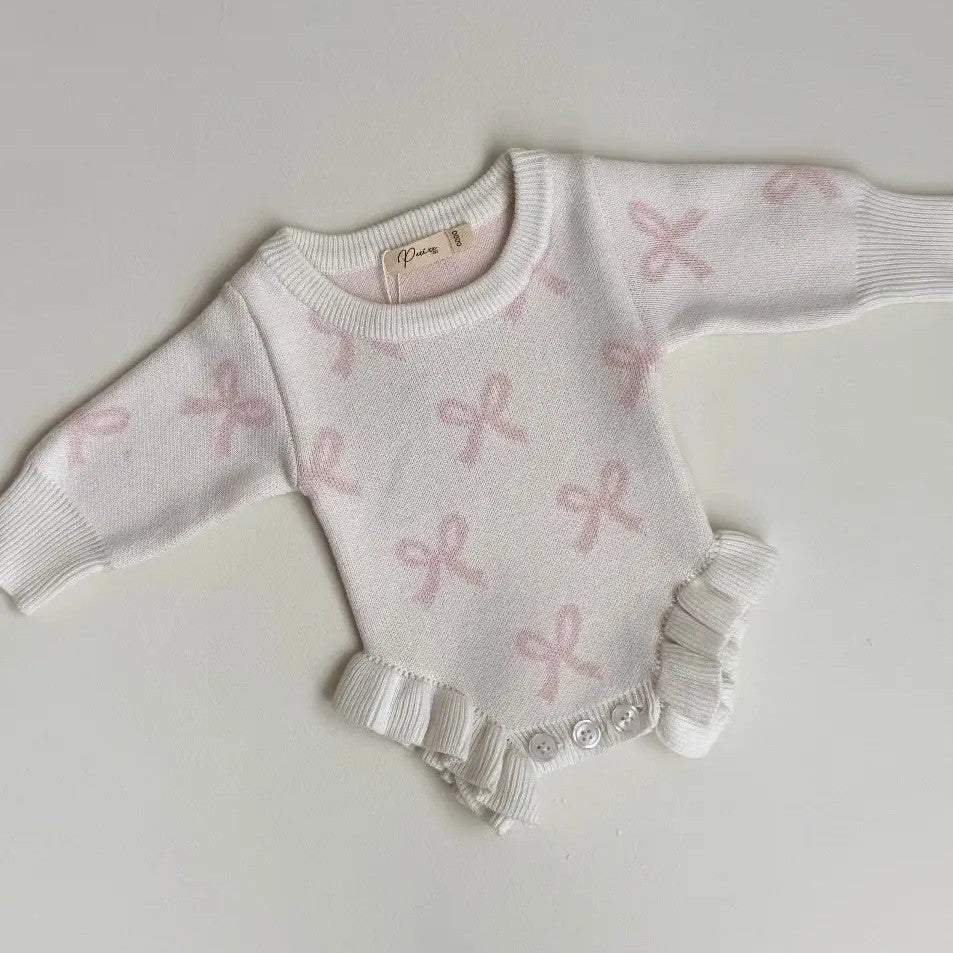 Baby sweater with pink bow pattern on a light gray background