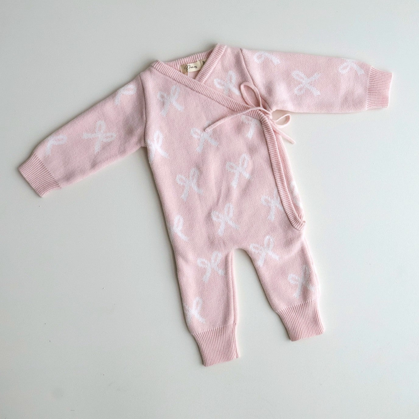 Pink baby romper with white floral patterns on a light gray background