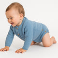 Baby in a blue knitted outfit crawling on a white surface