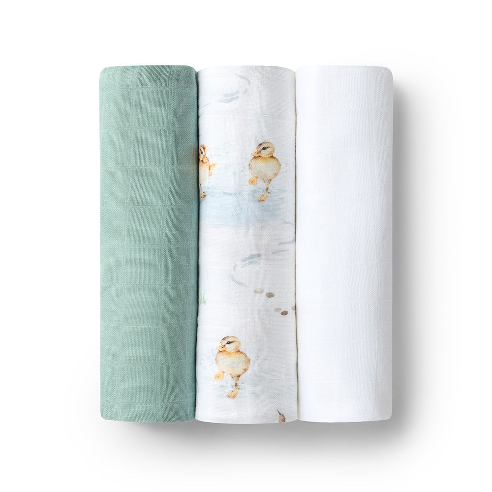 Three swaddle blankets, one green, one white and one with duck design, on a white background