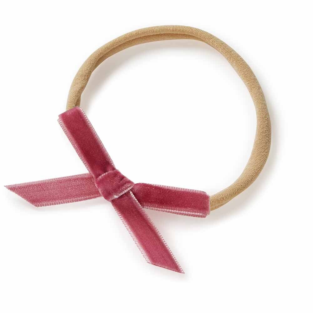 Beige hairband with a pink velvet bow on a white background