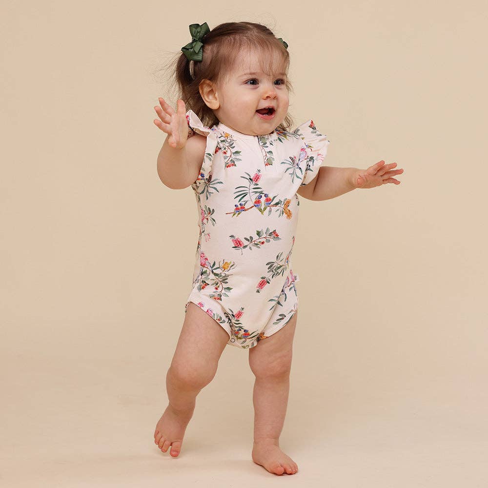 Baby wearing a floral onesie on a beige background