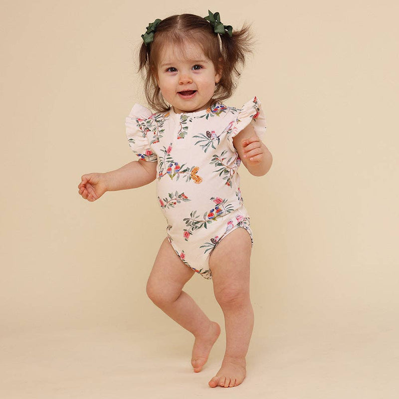 Baby wearing a floral onesie on a beige background