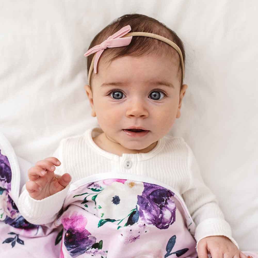 Baby wearing a floral outfit and headband on a white background