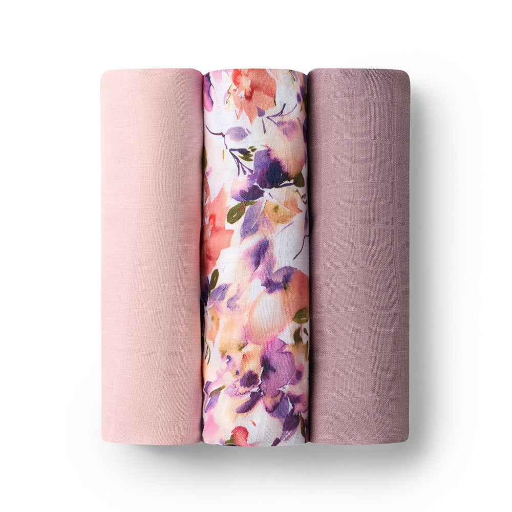 Three rolled-up pink muslin wraps with different patterns on a white background