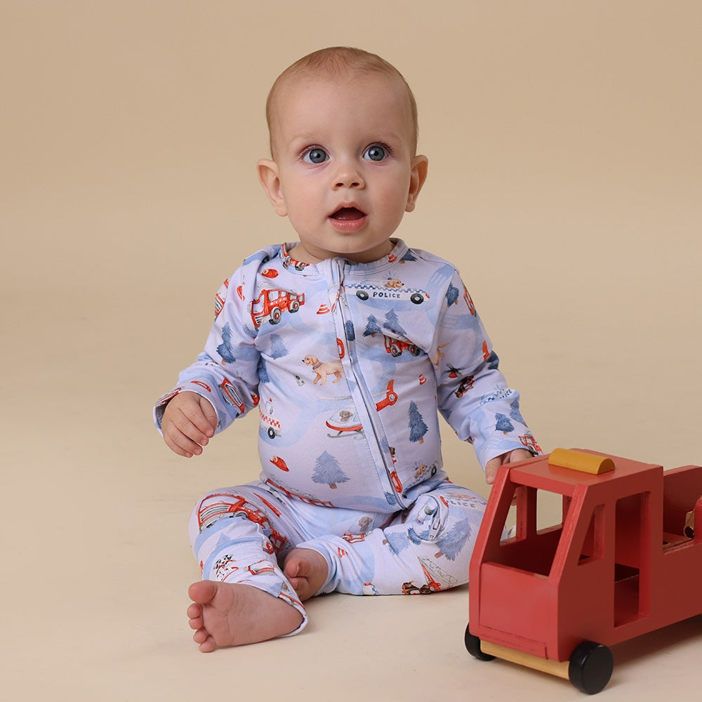 Baby in a patterned onesie with a red toy truck on a beige background