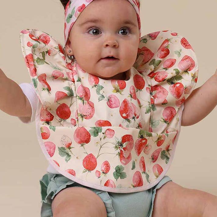 Baby girl wearing Snuggle Hunny strawberry patterned feeding bib from Meridian Baby