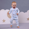 Child wearing a light blue pajama set with airplane pattern against a neutral background