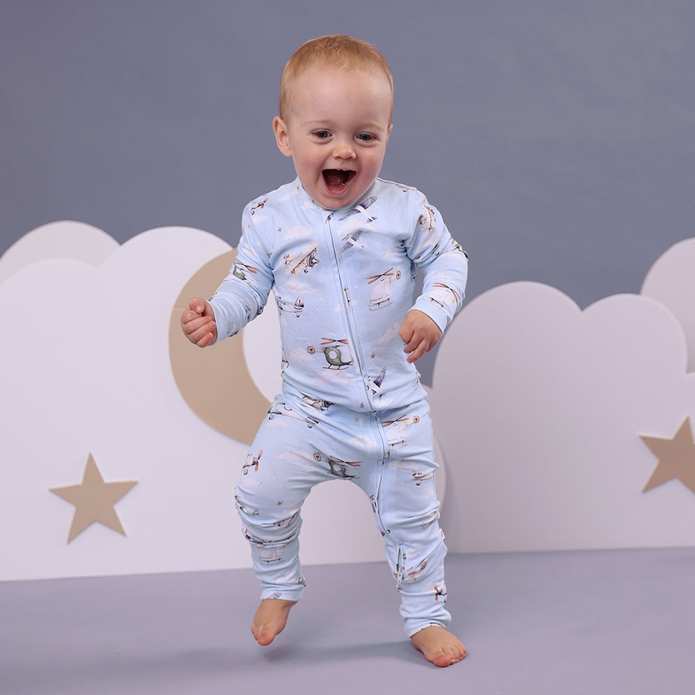 Child wearing a light blue pajama set with airplane pattern against a neutral background