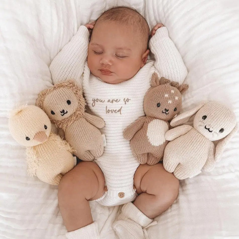 Newborn baby surrounded by soft toys on a white background